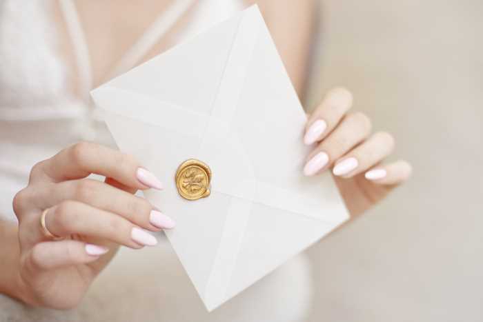 a wedding invitation in a woman's hands